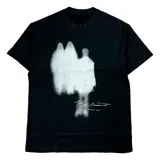 Remera negra de algodón con estampado frontal en blanco que simula dos figuras borrosas y una firma manuscrita con el texto "bullet hole" debajo.