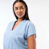 Blusa de manga corta en color azul con estampado de rayas verticales blancas, cuello en V con abertura y corte holgado.