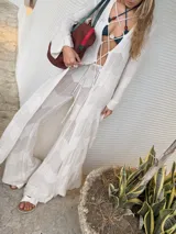 Saco largo de tejido de punto calado, color blanco, con mangas largas y cierre frontal mediante cordones entrecruzados.