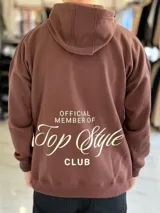Canguro oversize de color marrón, con capucha y estampa en la espalda con el texto "Official Member of Top Style Club".