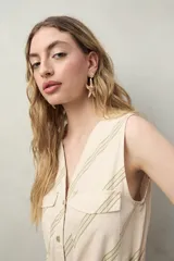 Mono largo sin mangas de algodón con estampado de hojas en tonos verde y beige. Tiene cuello en V, cierre frontal con botones, bolsillos laterales y cinturón de lazo.