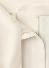 Pantalón recto de tiro medio color beige, con bolsillos laterales y un cinturón incorporado con detalle de flecos en los extremos.