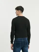 Sweater de punto con textura tipo waffle, color negro, de corte clásico con cuello redondo y mangas largas.