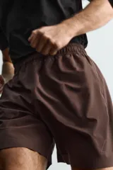 Pantalones deportivos cortos de Zara Athleticz, confeccionados en tejido técnico ligero y elástico. Presentan cintura elástica ajustable con cordón interior, bolsillos frontales, bajo con perforaciones decorativas y aberturas laterales, con detalle de logo estampado en la pierna.