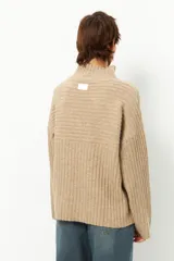 Polera gris de tejido tramado, cuello alto y mangas holgadas.