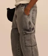 Pantalón de jean modelo baggy con bolsillos cargo laterales, cintura con trabillas y cierre frontal con botón y cremallera.