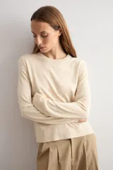 Sweater clásico de punto color beige, de cuello redondo y manga larga con diseño ajustado.
