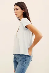 Remera básica de corte holgado, color negro, con mangas cortas y cuello redondo. Presenta un diseño con largo irregular y ruedo redondeado, confeccionada en algodón peruano con textura jaspeada.
