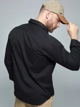Camisa de manga larga color marrón, con cuello clásico, cierre frontal con botones y dos bolsillos frontales con solapa en el pecho.
