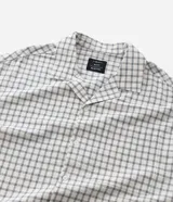 Camisa de manga corta para hombre con diseño boxy, confeccionada en tricolina de algodón con estampado de cuadros y textura sutil. Presenta cuello camisero, cierre frontal con botones y un bolsillo aplicado en el pecho.