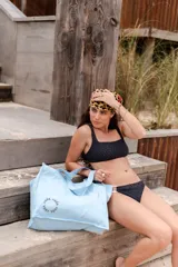 Bolso tipo tote bag color celeste con asas cortas y estampado de la palabra 'cada' en círculo.