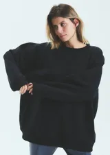 Buzo negro oversize de frisa esmerilada con cuello alto, hombros caídos, bolsillos laterales y estampa en la espalda con el logo de la marca en animal print.