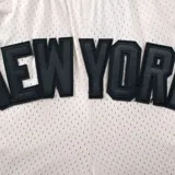 Short deportivo negro de tela de red, con cintura elástica ajustable con cordón. Estampado con el nombre "New York" en letras grandes y el logo de los Yankees.