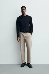 Pantalón de corte regular fit, color negro, confeccionado en tejido elástico. Presenta cintura elástica, cierre frontal con cremallera y botón, bolsillos laterales y bolsillos traseros de vivo.