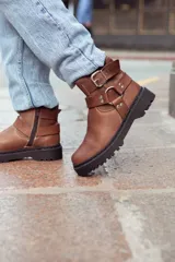 Botas de cuero color marrón con suela track y hebillas decorativas.