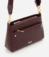 Cartera bandolera Satinato de material sintético en color bordó, con estructura firme y diseño rectangular. Cuenta con cierres metálicos dorados, bolsillo frontal con cierre, herrajes metálicos y correa ajustable y desmontable.