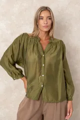 Camisa de organza blanca con cuello mao, diseño de manga larga tipo murciélago y cierre frontal con botones. Presenta un corte holgado y fluido.