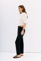 Pantalón blanco de tiro alto con elástico interno en la cintura, botones falsos y terminación con volado. Tiene bolsillos aplicados en delantero y falsos en espalda.