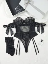 Body de encaje y transparencias color negro, con tirantes transparentes, varillas en el torso, bandas caídas en los brazos con lazo y ligas incorporadas.