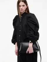 Vestido camisero blanco con botones frontales, cuello camisero, manga larga abullonada con puños ajustables y corte a la rodilla.