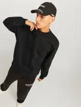 Buzo negro de manga larga y cuello redondo, de corte holgado y tejido de felpa suave.