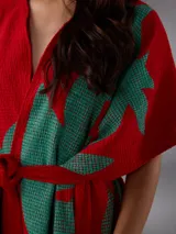 Capullo o kimono de paño 100% algodón, color rojo con estampado exclusivo en tono verde, de morfología amplia y envolvente, con bolsillos laterales y cinto independiente para ajustar la cintura.