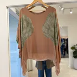 Blusa de corte amplio y vaporoso en tono camel, con cuello redondo y mangas murciélago caídas. Presenta un diseño estampado en los laterales que simula hojas en tonos verdosos.