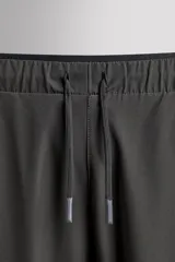 Pantalón de jogging negro confeccionado en tejido técnico ligero y elástico, corte slim fit, con cintura elástica ajustable con cordón, bolsillos laterales y trasero con cierre de cremallera, bandas reflectantes en las piernas y bajos ajustables con cremallera.