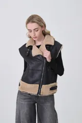 Chaleco sin mangas de cuero sintético negro con interior y detalles de piel sintética en color beige. Presenta cierre frontal asimétrico, cuello solapa y correas ajustables en la cintura.