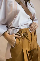Short color tostado con pinzas frontales, trabillas cruzadas decorativas y cinturón talabartero incluido.