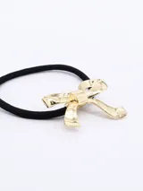 Colero (liga para el pelo) negro con un dije metálico en forma de moña dorada.