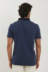 Remera tipo polo de manga corta, color azul marino jaspeado, con cuello y ribetes en las mangas de color azul oscuro y blanco.