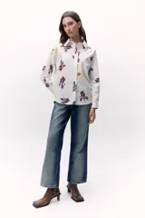 Camisa blanca con estampado floral en tonos amarillo, rojo y azul, de corte recto y manga larga.