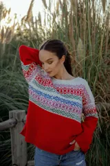 Sweater rojo de lana merino con cuello redondo y mangas largas. Presenta un canesú con diseño geométrico multicolor en tonos blanco, rojo, azul, verde y rosa.