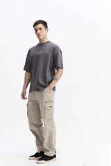 Pantalón cargo de corte baggy, color beige, con bolsillos laterales tipo cargo con cierre y solapa, y diseño de pierna ancha.