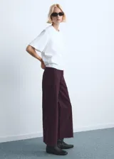 Jeans de corte wide leg y tiro medio, color bordó, con diseño de pernera ancha y terminación sin dobladillo en el bajo.