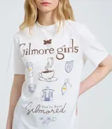 Remera de algodón color blanco con cuello redondo y manga corta. Presenta un estampado temático de la serie Gilmore Girls en la espalda con diseño de taza de café y texto descriptivo.