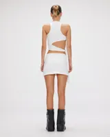 Conjunto de dos piezas compuesto por un top de cuello alto con diseño cut-out lateral y nudos, y una minifalda ajustada. Confeccionado en tejido elástico premium con forrería.