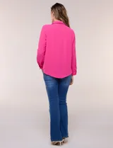 Blusa verde de calce holgado y caída fluida, confeccionada en tejido tipo crepé. Cuenta con cuello camisero con solapa, escote en V y cierre parcial al frente con tres botones metálicos. Las mangas son largas con puños abotonados.
