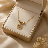 Collar de acero con baño de oro, compuesto por una cadena fina con esferas decorativas y un dije circular con el diseño del árbol de la vida rodeado de cristales.
