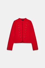 Chaquetas de cuello redondo y manga larga, de color rojo. Cuenta con detalle de botones dorados frontales y en los puños, con cierre delantero con corchetes ocultos.