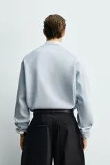 Sudadera de corte regular fit confeccionada en tejido de mezcla de algodón con estructura de piqué y efecto lavado. Presenta cuello redondo, manga larga y acabados en rib en puños y ruedo.