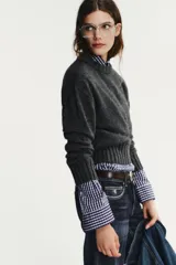 Jersey de punto con cuello redondo y manga larga, con acabados en rib ancho a tono y bajo asimétrico.