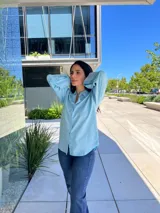 Camisa celeste de manga larga con puños anchos, cuello clásico y cierre frontal abotonado.