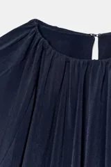 Top azul marino de tejido fluido con cuello redondo y manga larga abullonada con aberturas. Presenta una abertura en la espalda con tira del mismo tejido y cierre de ganchos metálicos.