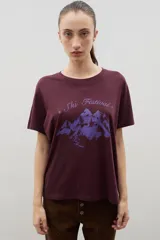 Remera de algodón con cuello redondo y mangas cortas. Presenta un estampado frontal en color violeta con el texto 'Ski Festival' y un diseño de montañas con un esquiador.
