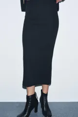 Falda midi de tiro medio confeccionada en tejido soft, con cintura elástica y abertura en la parte posterior.