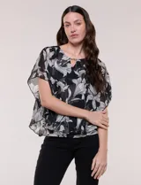 Blusa de gasa semitransparente con estampado floral en blanco y negro, de silueta holgada tipo capa con mangas cortas amplias y escote redondo con detalle metálico.