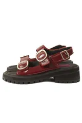 Sandalias de plataforma estilo chunky en color negro, confeccionadas en material sintético efecto charol. Presentan dos tiras ajustables con hebillas metálicas plateadas y una tira trasera con hebilla para mayor sujeción. Suela dentada de goma.