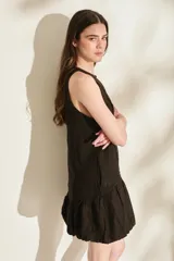 Vestido corto de lino color bordó, sin mangas, con escote redondo, costuras decorativas con flecos y falda estilo globo con volados en el ruedo.